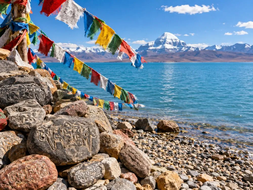 Gebetsfahnen und Mani-Steine am Ufer des Manasarovar-Sees mit dem Mount Kailash im Hintergrund